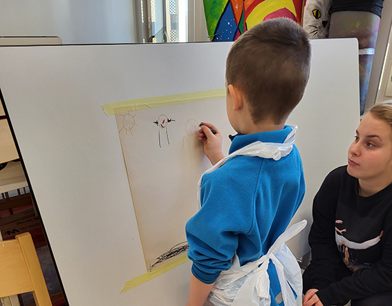 Lapsi maalaamassa vahaliiduilla, aikuinen ohjaa ja auttaa vieressä.