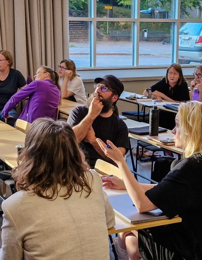 Vuoden 2024 ekokoordinoinnin pilottiohjelman osallistujat pohdiskelevat ryhmissä vastauksia tietovisan kysymyksiin.
